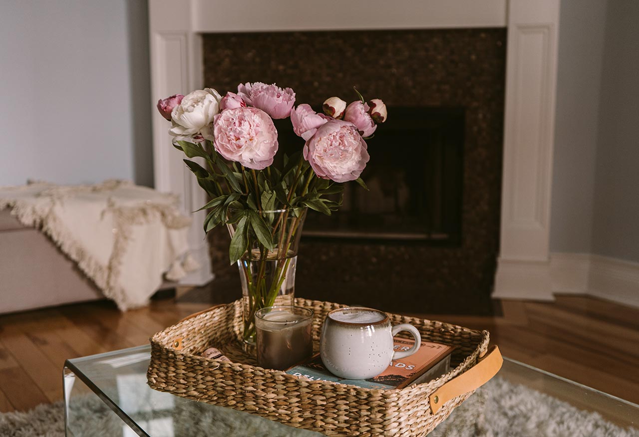 een knusse woonkamer met bloemen op de salontafel en een haard op de achtergrond