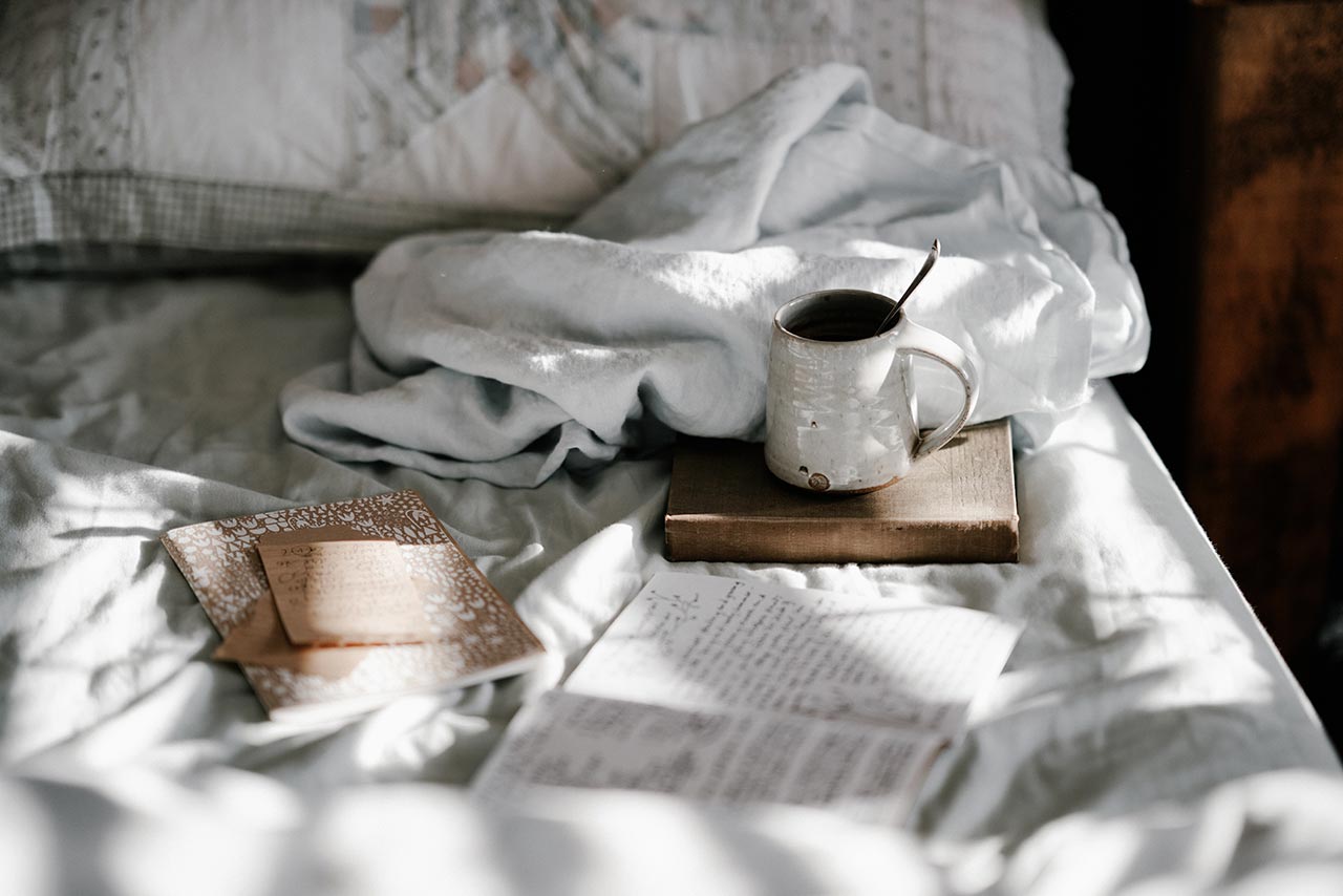 een bed met daarop boeken en papieren om op te schrijven