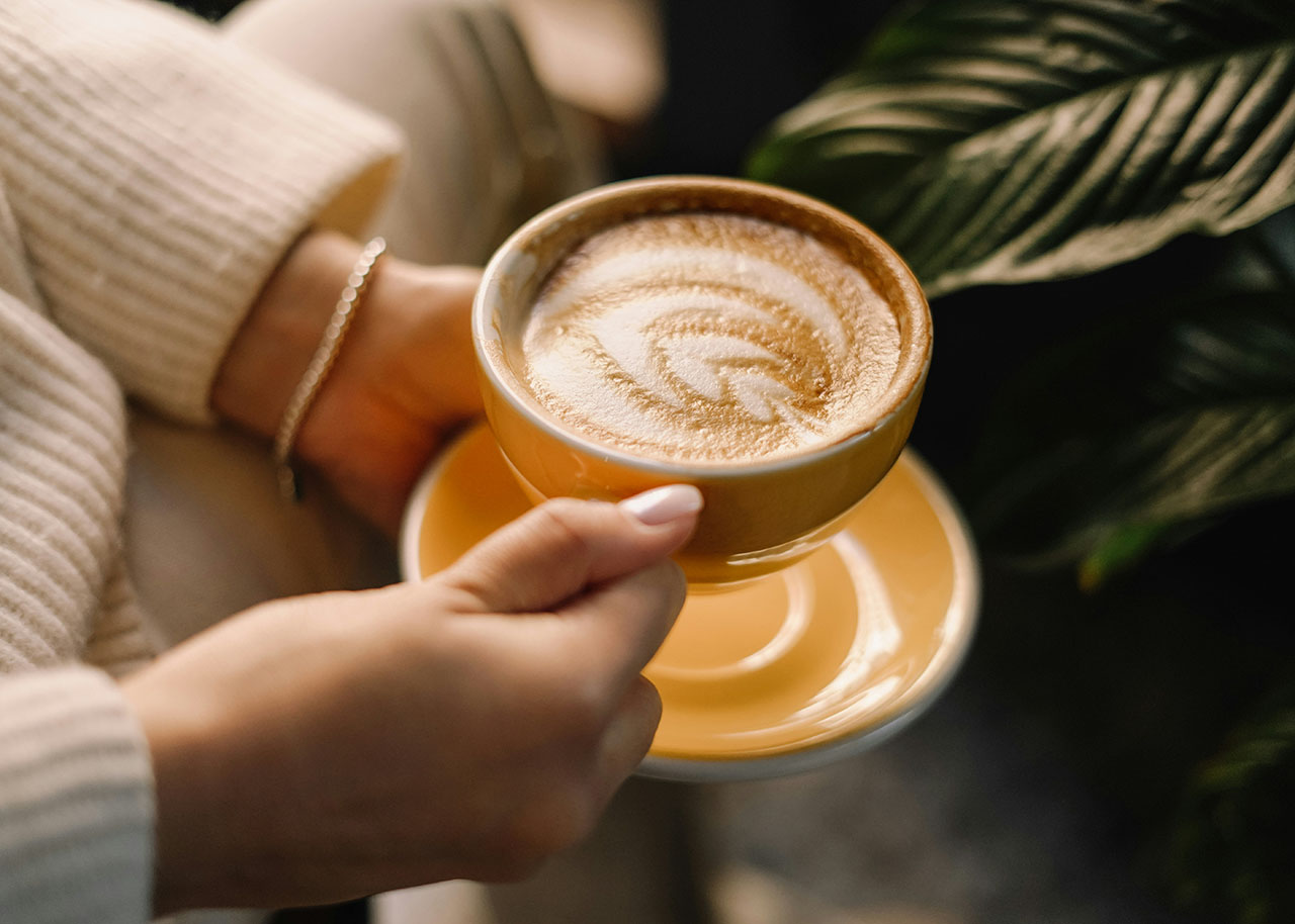 a woman on a bed with a laptop, holding a cup of coffee - next steps to future-proof your small business