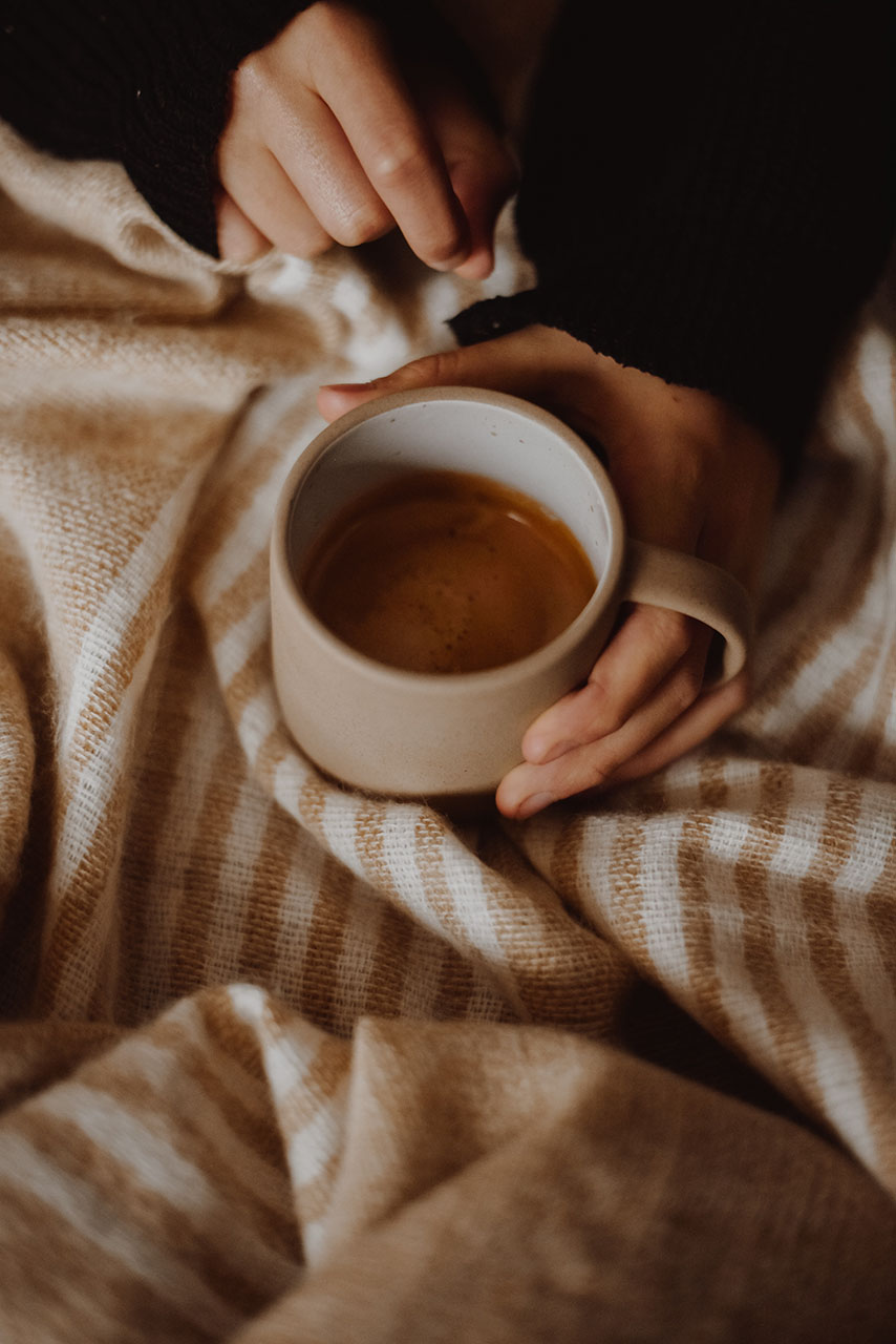 een vrouw die een keramieke kop met een warme drank vasthoudt - creëer jouw warme winterthuis