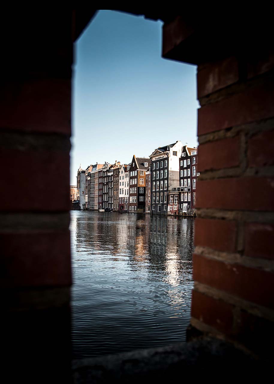 grachtenpanden in Amsterdam gefotografeerd door een opening - mindful fotograferen